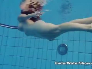 Redheaded cutie swimming nude in the pool
